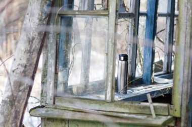 Terkedilmiş eski bir evde güzel bir Japon termosu. Eski bir pencere pervazında çelik termos. Ön görünüm.