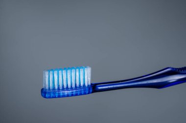 Bütçe diş fırçası mavisi. Gri arkaplanı fırçala. Temizlik aleti. Ön görünüm.