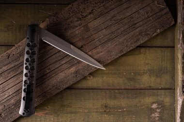 Hafif saplı katlanmış bıçak. Delikli bıçak sapı. Ahşap bir arka planda bıçak. Keskin büyük bıçak..