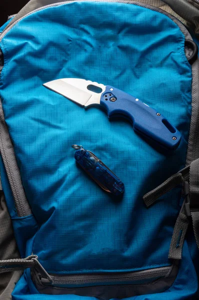 Niebieski nóż i niebieski plecak. Niebieski nóż na niebieskim tle. Nóż z małym ostrzem. Nóż EDC. — Zdjęcie stockowe