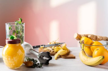 Soyulmuş zencefil, mutfak bıçağı ve mikser. Zencefil, meyve ve bal. Zencefilli yemek yap. Ön görünüm.