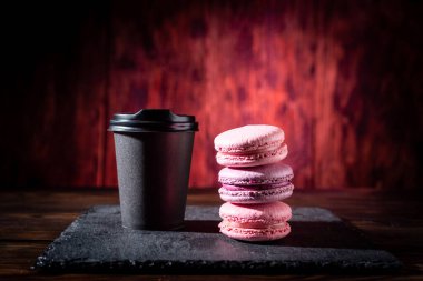 Glass of coffee and cookies. Black glass and red cookies. Black coffee and French biscuits. Macaroon cookies. Bright red background.