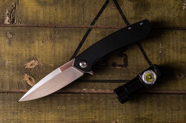 Ordu kasasında çakı ve el feneri. Bıçak ve fener masada. Keskin bir bıçak ve küçük bir fener. Yukarıdan görüntüle.