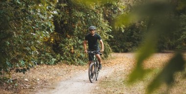 Bicycle training of an adult man in the forest outdoors. Healthy and active lifestyle.