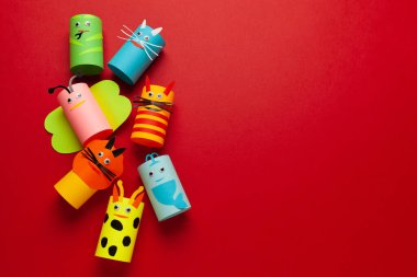 Kırmızı arka plandaki kağıt rulolarından ev yapımı hayvan figürleri. Yaratıcı çocuk oyuncakları, sıfır israf. Metin için alanı kopyala.