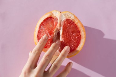 Two female fingers in grapefruit, woman masturbation and sex concept. Vagina and clitoris symbol.