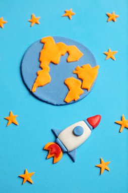Kid (child) rocket in space, adventure and science. Stars, planet earth. Plasticine art, cartoon.