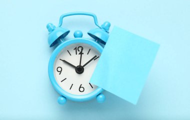 Mavi çalar saat ve bir hatırlatma notu. Zaman yönetimi konsepti. Metin için alanı kopyala.