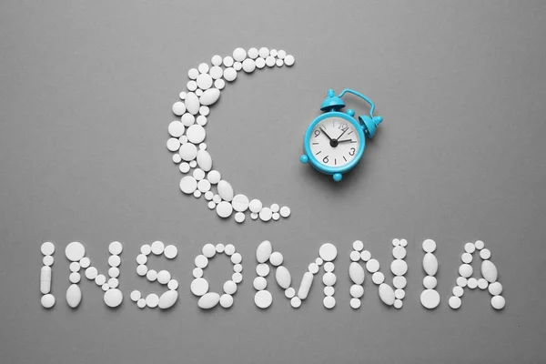 Sleeping pills and an alarm clock, insomnia concept. Medications for fatigue and sleep problems.