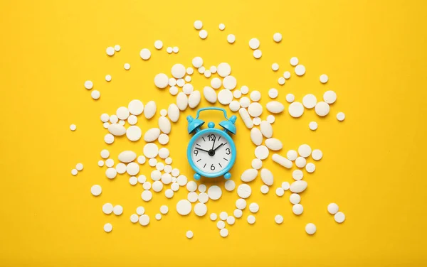 Sleeping pills and an alarm clock, insomnia concept. Drugs for treating sleep problems.