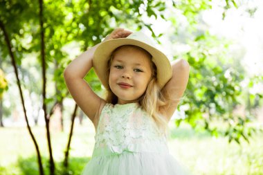 Parkta ya da dışarıda gülümseyen şapkalı şirin kız modelinin portresi. Mutlu çocukluklar, yaz tatilleri ve tatiller..