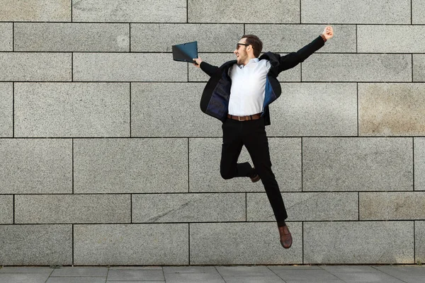 Young businessman in a suit jumping for joy, success, victory.