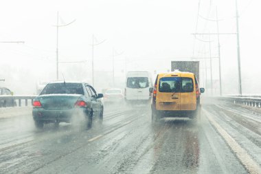 Çamurlu ve kar fırtınalı yollar boyunca araba sürülür. Kar fırtınasında şehir trafiği.