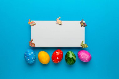 Mavi arka planda tavşanlı parlak paskalya yumurtaları. Retro renkli bahar dekorasyonu. Metin için alanı kopyala.