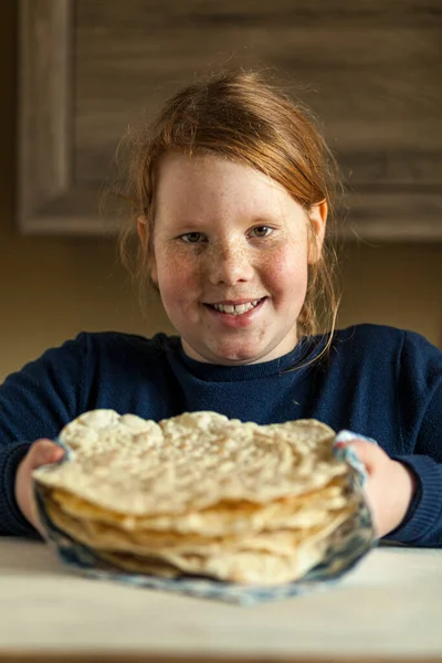 Red-haired fat girl with freckles holding home-made pita bread (lavash) in her hands and smile. Homemade national pastries.