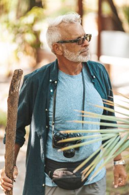 Yaşlı bir adam parkta yürüyor, egzotik bir tatil ve seyahat. Emeklilikte yeni izlenimler, aktif yaşam tarzı.