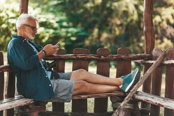Anciano Está Escribiendo Mensaje Por Teléfono Mientras Relaja Banco Estilo — Foto de Stock