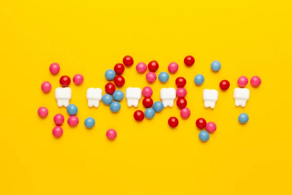 Teeth and sweet candies on a yellow background.