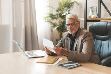 Mahkeme celbi. Hüsrana uğramış olgun bir adam ofiste bir masada oturuyor ve elinde bir vergi mektubu tutuyor. Mali sorunlar ve borç.
