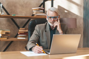 Problemin çözümü. Taşralı bir işadamı bir fikri kağıda yazmaya odaklanıyor. Ofisteki masaüstünde oturuyor..