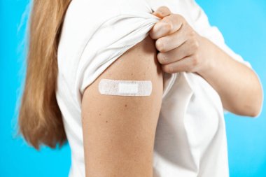 İnsanları aşılamak için. Mavi arka planda iğne yaptıktan sonra alçıyla bir el..