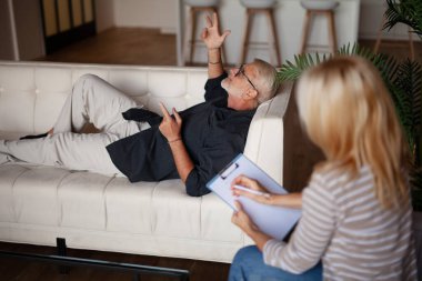 Hasta ve doktor. Olgun bir adam bir psikologla seans sırasında kanepede uzanıyor. Açık konuşmak, problem analizi..