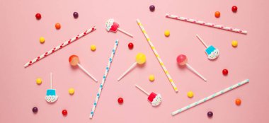 Çocuk doğum günü partisi, pembe arka plan (desen). Tatlı şekerler, parlak balonlar, şenlikli mumlar, kek ve pipetler..