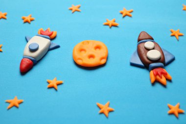 Creative craft plasticine rocket in open space, astronaut dreams. Stars, moon. Cartoon art.