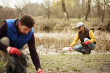 Bağış gönüllüleri ormandaki çöpleri topluyor, doğayla ilgileniyor. Parkta bahar temizliği, çöpler ve çöpler..