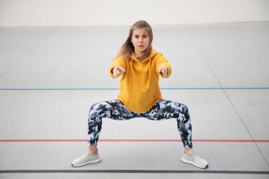 Sarı bluzlu ve askeri taytlı güzel kadın açık hava sporlarından önce ısınıyor..