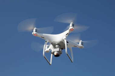 Mavi gökyüzü arka planında İHA. Fotoğraf makinesi olan uzaktan kumandalı kuadrokopter. Uçan robot..