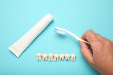 Sağlıklı beyaz dişler, diş macunu ve mavi arka planda el fırçası..