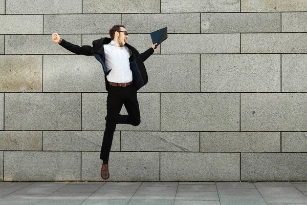 Young man in suit is jumping with happiness, success and fun.