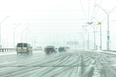 Çamurlu ve kar fırtınalı yollar boyunca araba sürülür. Kar fırtınasında şehir trafiği.