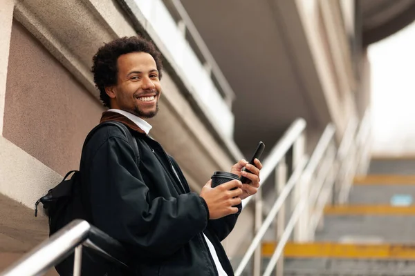 Smile african student with phone on background of stairs. Digital generation.