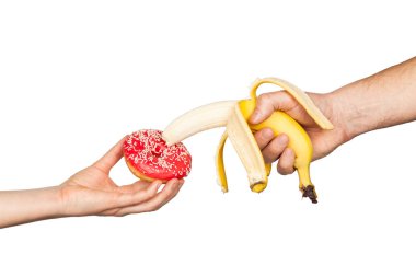 Erotic banana and donut in the hands as a symbol of the penis and vagina isolated on a white background. The relationship between a man and a woman, sex and passion.