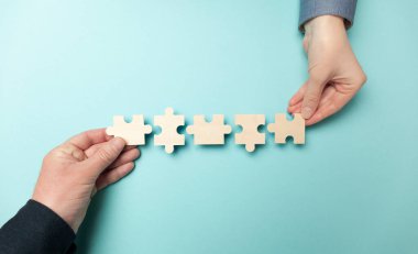 Mavi arka planda iki el bulmacaları birbirine bağlıyor. İş ortaklığı ve takım çalışması. Başarı için işbirliği yapan insanlar.