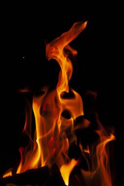 Fiery flame with sparks on a black background. Texture (element) for barbecue or cooking.