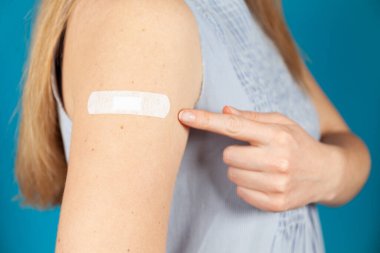 Aşıdan sonra. Kadın yapışkan alçıyı işaret ediyor. Ön kolda aşınma var..