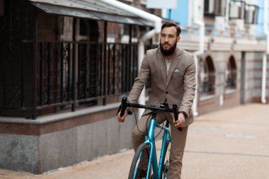 Takım elbiseli bir işadamı işe bisikletle gider. Çevre dostu şehir ulaşımı.