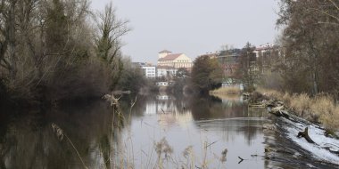 Panoramic of a river with reflections of town in autumn.