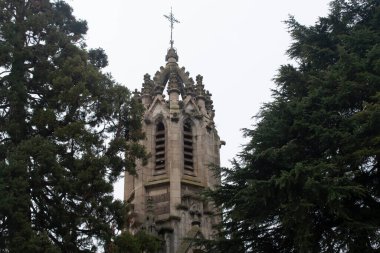 Ağaçların arasından görülen bir kilisenin çanı..