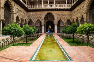 Seville, Spain -- May 20, 2022. A wide angle photo looking iver a reflecting pool inside the Alcazar.