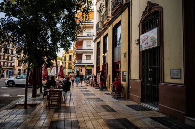Seville, Spain-- May 22, 2022. A photo of a busy street in Seville where people are dining outdoors.