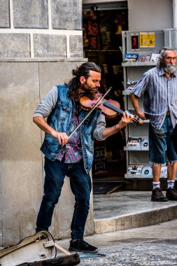 Granada, İspanya -- 5 Haziran 2022. Bir sokak müzisyeni Granada 'da bir sokak köşesinde keman çalar; başka bir adam ona dik dik bakar..
