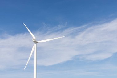 wind turbine in the wind with blue sky in background under sun light