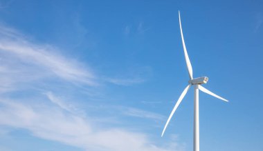 wind turbine in the wind with blue sky in background under sun light