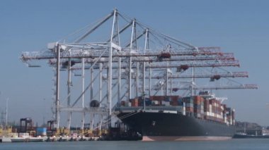 Büyük konteyner yüklü ve İngiltere'de Southampton bağlantı noktası rıhtımda yük taşıyan boş bir gemi. Bir Fs7 kamera çekim. Tüm logolar sonrası kaldırıldı.