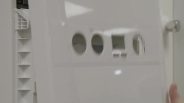 Gaz merkezi ısıtma kazanına hizmet eden kadın mühendis ön paneli kaldırıyor..