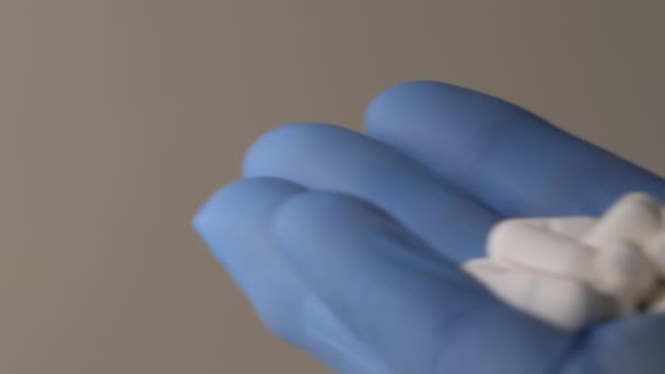 Närbild skott av en hand i blå latexhandskar innehav piller. — Stockvideo